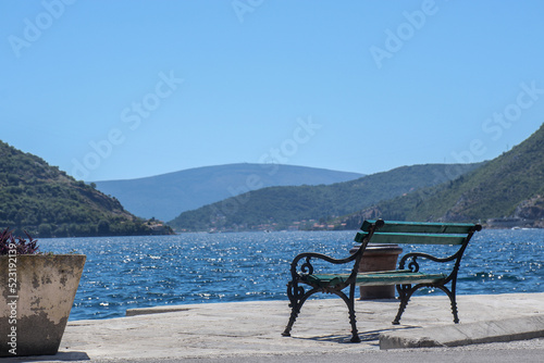 Old vintage empty bench by the sea and beautiful landscape with mountains