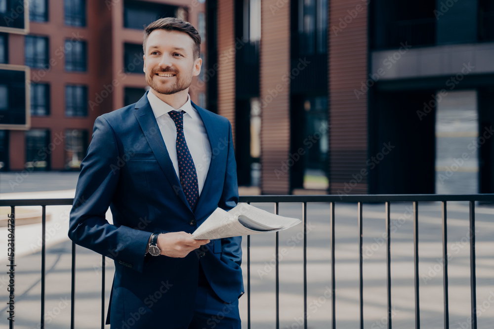Fototapeta premium Happy office worker on break standing while holding newspaper