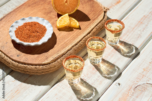 Mexican mezcal shots with slice of orange fruit adn chili