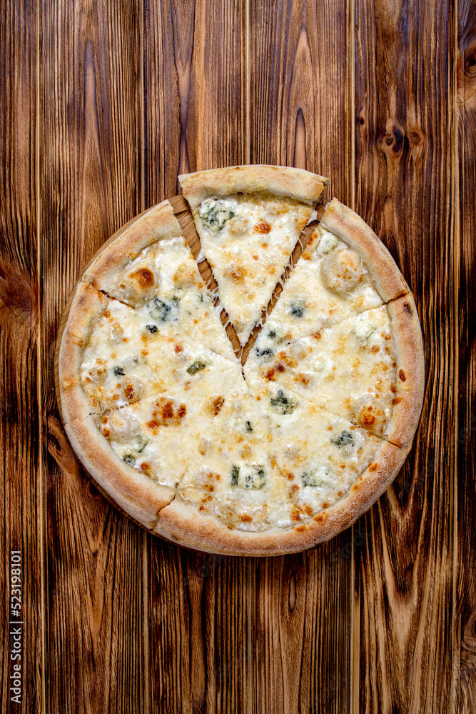 Pizza with four cheeses, mozzarella, blue cheese, Parmesan cheese. Italian cuisine. On a wooden background. View from above.