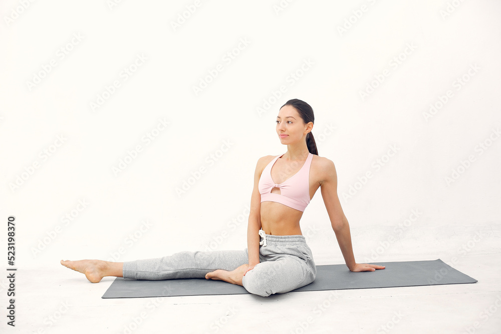 Fototapeta premium A beautiful girl is engaged in a yoga studio