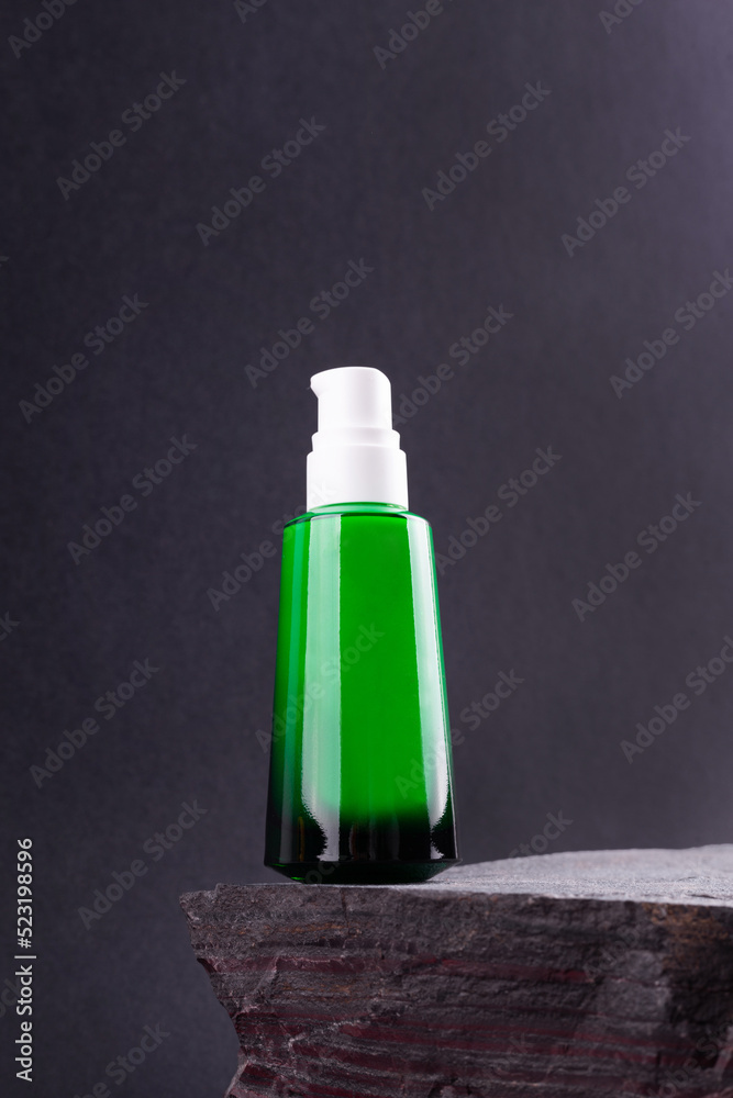 Opened green Bottle on stone isolated black background close up. Brand packaging mockup. Essence, skincare beauty product, cream or serum. Natural herbal cosmetics concept. Opened green Bottle on stone isolated black background close up. Brand packaging mockup. Essence, skincare beauty product, cream or serum. Natural herbal cosmetics concept.