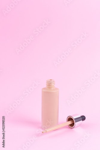 Opened liquid foundation cream with pipette unbranded bottle on a pink background. BB cream for professional make-up, eyedropper for applying to the face. Cosmetic female accessory, fluid. Mock up . photo