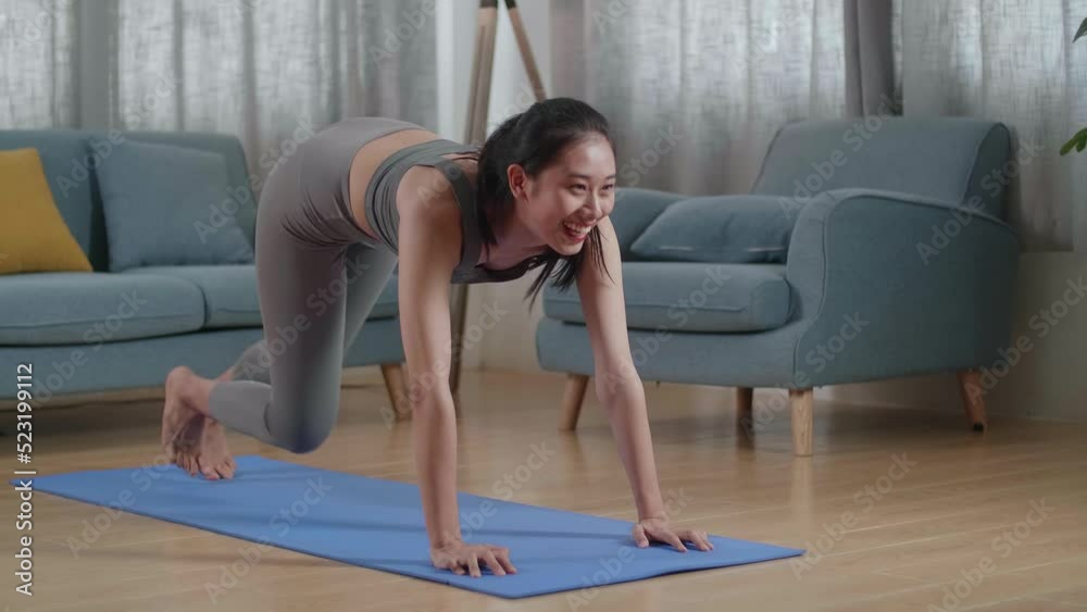 Young Asian Athletic Female In Sports Clothes Doing Cardio High Knees And Core Strengthening Exercises During Workout On The Mat At Home
