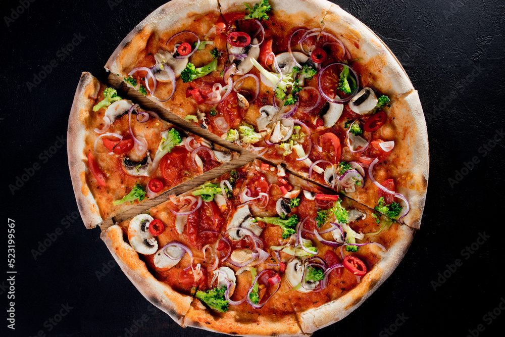 Vegan pizza with tomato sauce, cherry tomatoes, mushrooms, broccoli, red onion on black background. View from above