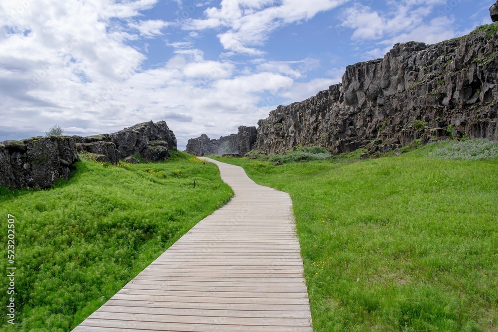 Unrecognizable tourists on wooden path in Thingvellir area, Iceland with geological formations