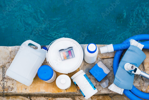 High angle view of equipment for testing the quality of pool water, vacuum cleaner and chemical cleaning products at the edge of swimming pool
