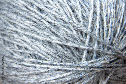 Clew of light gray melange thread close-up full frame. Selective focus.