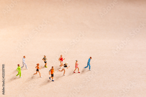 Miniature People exercising while running in a group on the beach. Living an active lifestyle concept