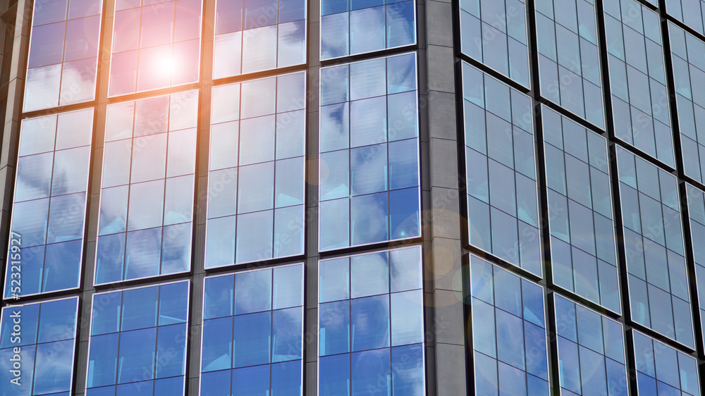 Modern glass facade against blue sky. Bottom view of a building in the business district. Low angle view of the glass facade of an office building. Modern glass facade against blue sky. Bottom view of a building in the business district. Low angle view of the glass facade of an office building.