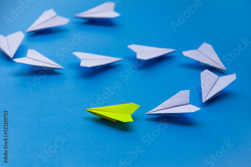 Yellow paper plane origami leading white planes on blue background. Leadership skills concept