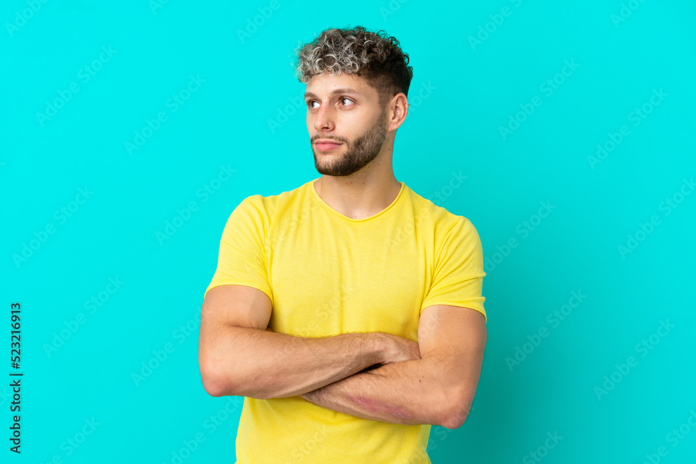 Young handsome caucasian man isolated on blue background looking to the side