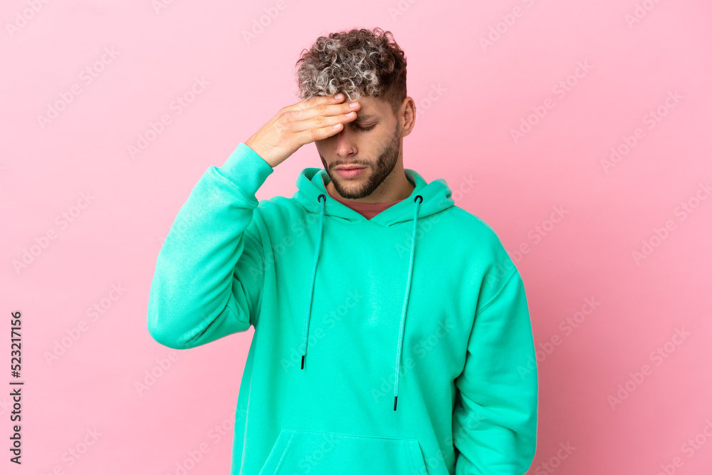 Young handsome caucasian man isolated on pink background with headache