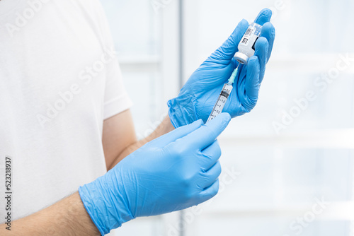 Doctor hand in blue gloves holding covid-19 vaccine preparing for vaccination shot, medicine and drug concept. (select focus)