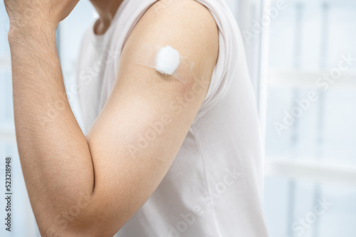 A man with medical plaster on arm after get covid 19 vaccine