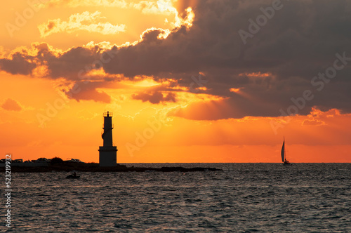 View of the island of Formentera harbor and its lighthouse at sunset with sailboats sailing by. Travel and tourism concept