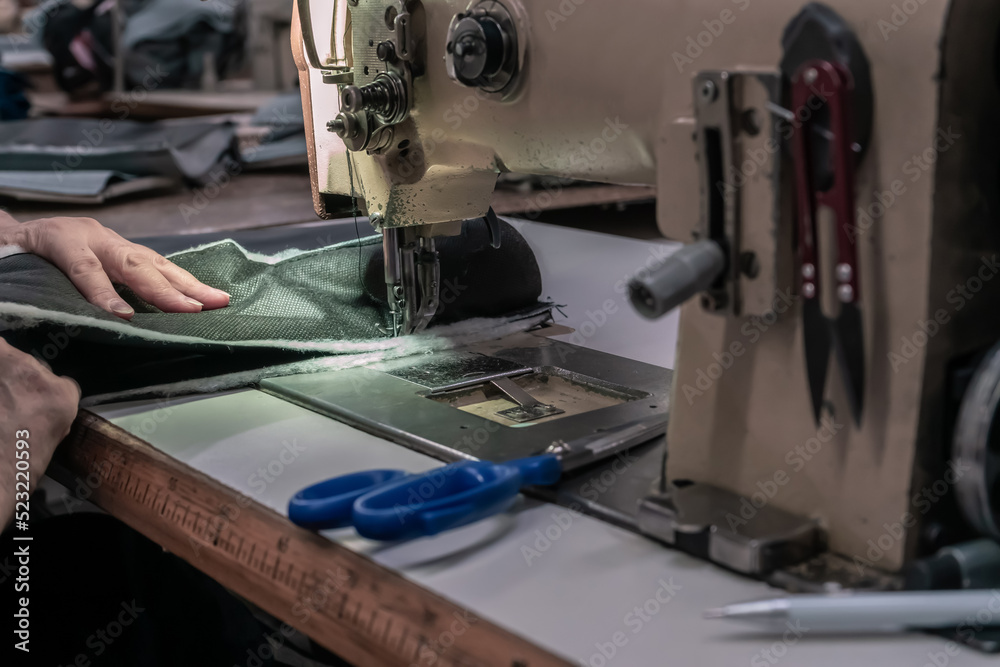Fototapeta premium The seamstress sews on an old sewing machine, threads the fabric. Women's hands