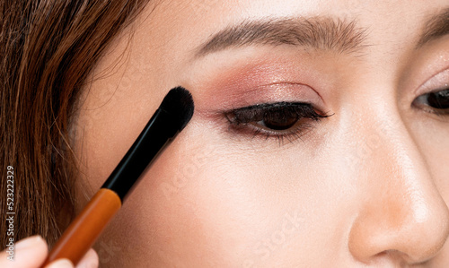 Print op canvas Closeup ardent young woman with healthy fair skin applying her eyeshadow with brush