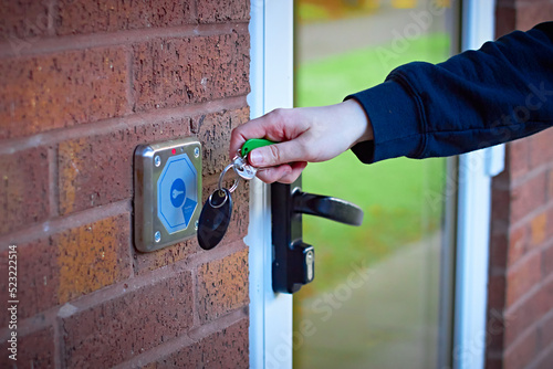 White womans hand using magnetic key fob to gain access to shared accommodation from outdoors photo