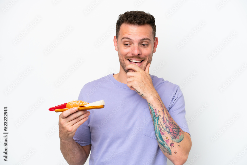 Young caucasian man holding sashimi isolated on white background looking to the side and smiling Young caucasian man holding sashimi isolated on white background looking to the side and smiling
