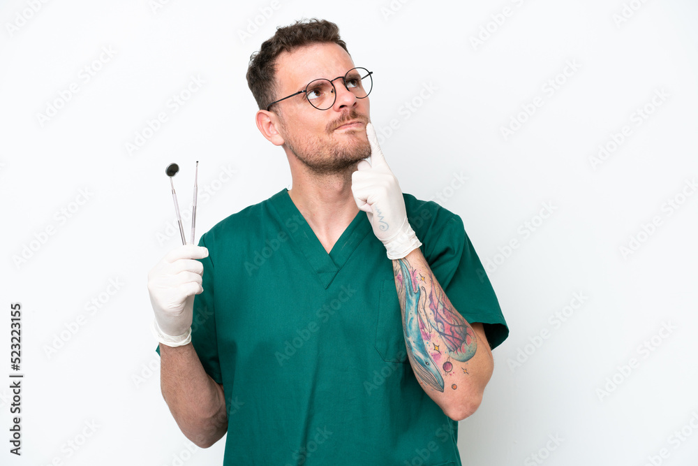 Young caucasian dentist man isolated on white background having doubts while looking up Young caucasian dentist man isolated on white background having doubts while looking up