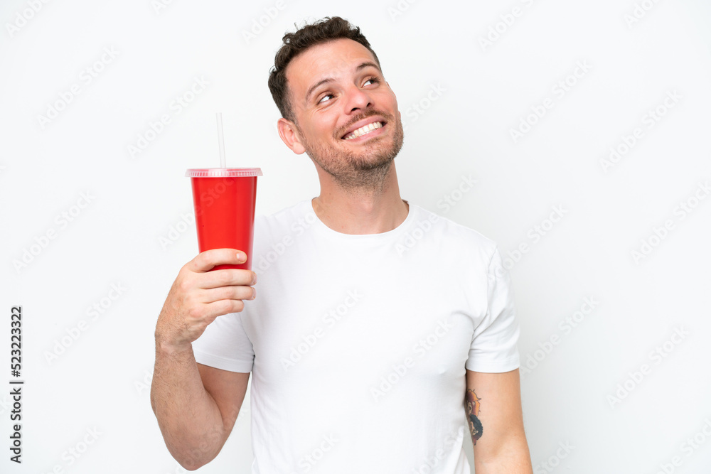 Young caucasian soda holding soda isolated on white background looking up while smiling Young caucasian soda holding soda isolated on white background looking up while smiling