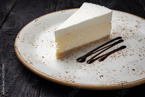 piece of cheesecake with cream and chocolate on a white plate photo