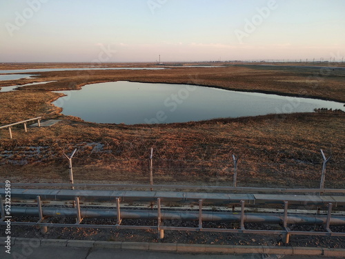 A fence with barbed wire and a view of the arctic tundra. Varandey  Russia.