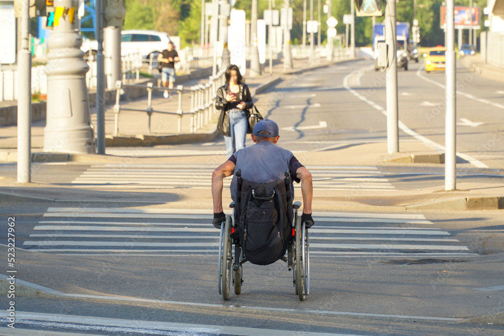 A disabled person in a wheelchair crosses the road at a pedestrian crossing.