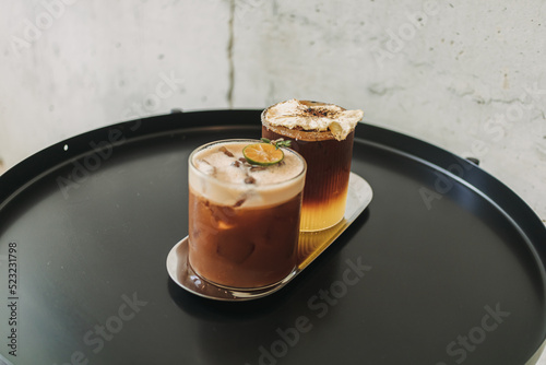 Two iced yusu orange coffee special drinks served on black table in the cafe. photo