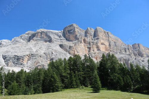 Val Badia, Italy-July 17, 2022: The italian Dolomites behind the small village of Corvara in summer days with beaitiful blue sky in the background. Green nature in the middle of the rocks. photo