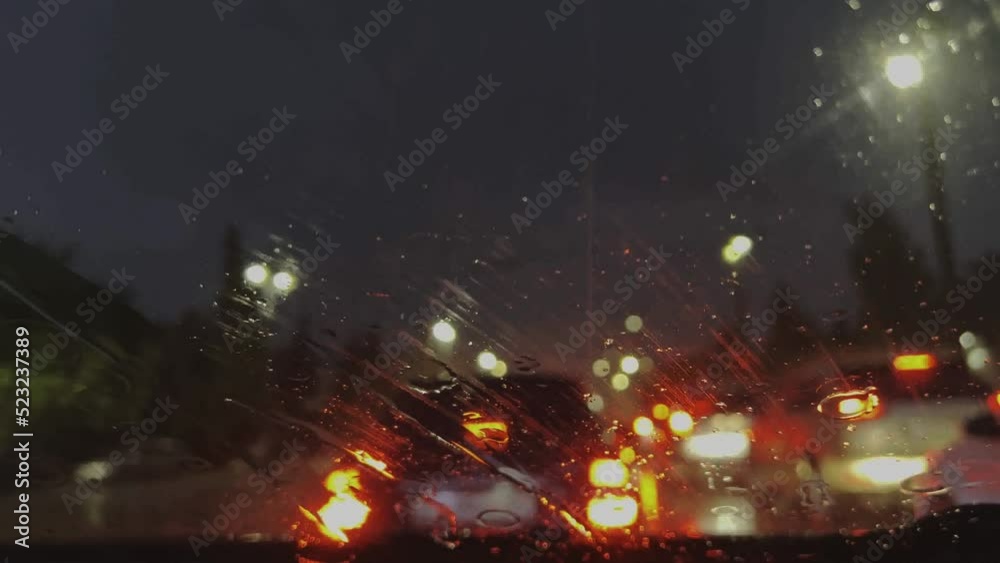 Raindrops on the windshield of the car. The car is driving through the streets of the evening city during a heavy downpour, blurred background traffic lights. High quality 4k footage Raindrops on the windshield of the car. The car is driving through the streets of the evening city during a heavy downpour, blurred background traffic lights. High quality 4k footage