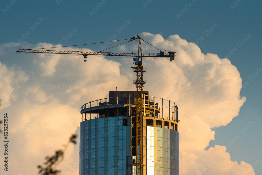 grua torre ubicada en un edificio en construccion, con nube tormentosa de fondo en el atardecer. trabajo en altura, construccion. grua torre ubicada en un edificio en construccion, con nube tormentosa de fondo en el atardecer. trabajo en altura, construccion.