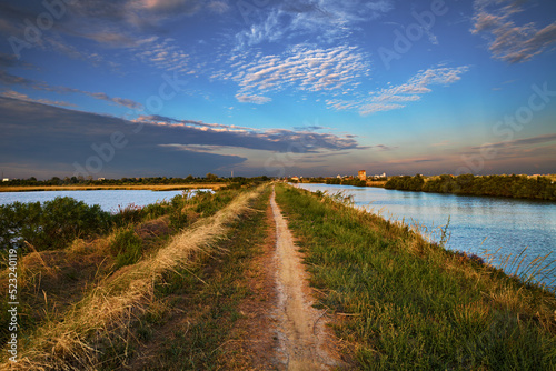 Comacchio, Emilia Romagna, Ferrara, Italy: landscape at sunset of the swamp with the path that crosses the lagoon Valli di Comacchio in the nature reserve Po Delta Park