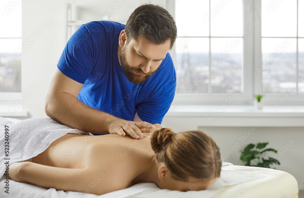 Male therapist massage female patient lying on table in wellness clinic or salon. Man masseur or physiotherapist help woman client relieve back pain. Recovery and rehabilitation concept. Male therapist massage female patient lying on table in wellness clinic or salon. Man masseur or physiotherapist help woman client relieve back pain. Recovery and rehabilitation concept.