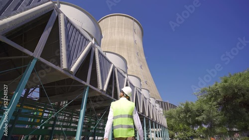 Cooling towers in power station.
The engineer is walking between the towers inside the power plant.
