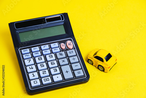 Toy car and calculator yellow background.Concept buying car.