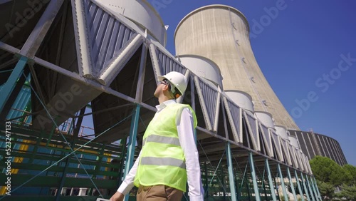 Nuclear power plant.
The engineer walking inside the plant looks at the cooling towers.
