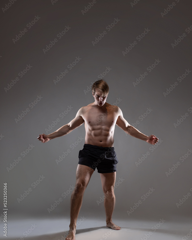 young muscular man in an expressive pose, artistic pose of the hero with outstretched arms. Beautiful muscles. extraordinary athletic body. Portrait on a gray background young muscular man in an expressive pose, artistic pose of the hero with outstretched arms. Beautiful muscles. extraordinary athletic body. Portrait on a gray background