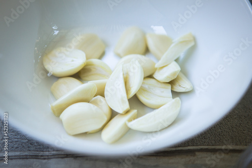 Peeled garlic cloves on a white plate close-up.