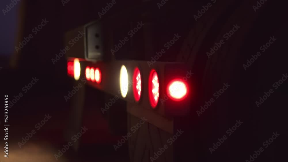 Tail lights blink on back of semi truck while backing up, with rack focus