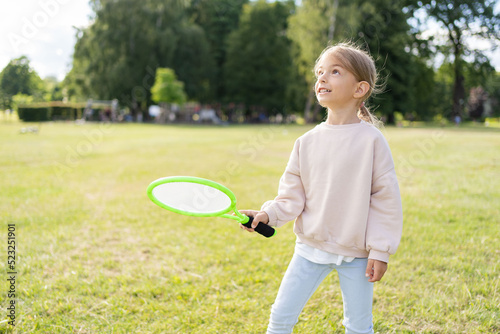  Little girl having fun in the park, playing badminton.