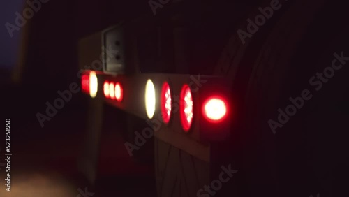 Tail lights blink on back of semi truck while backing up, with rack focus