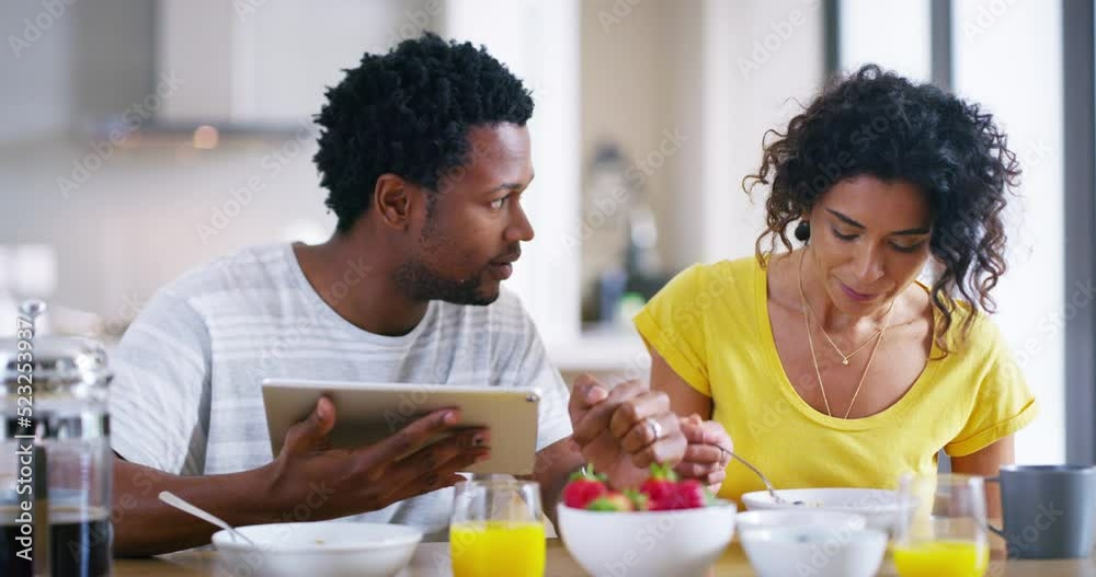 Happy and excited couple searching for a home online using a tablet while having breakfast in the morning. Young African American lovers browsing the internet are surprised by social media fake news Happy and excited couple searching for a home online using a tablet while having breakfast in the morning. Young African American lovers browsing the internet are surprised by social media fake news