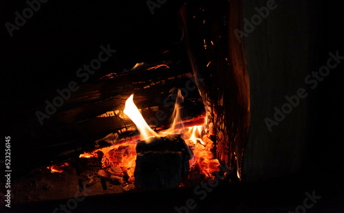 Wood in the fireplace. Burning firewood and fire flames on a dark background. Heating the house with a fireplace.