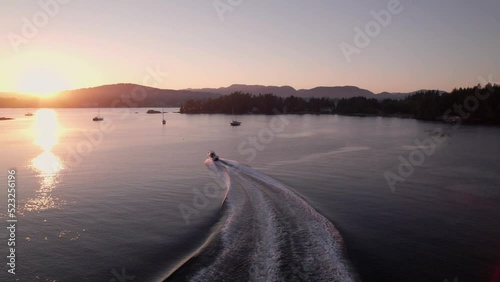 Aerial footage motor boat at sunset, Whiffen Spit, Sooke Harbour, calm water, ocean, Vancouver Island. 5.4K TO 4K 24FPS photo