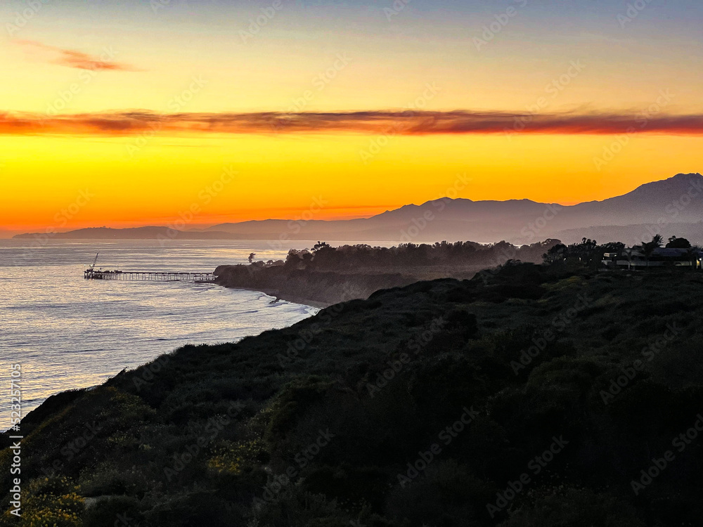 Yellow Sunset along the Pacific Ocean coastline.  Casitas Pier of Carpinteria in the background with Santa Barbara.