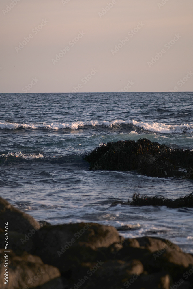 durante el ocaso se ven las olas rompiendo en las rocas de la playa durante el ocaso se ven las olas rompiendo en las rocas de la playa