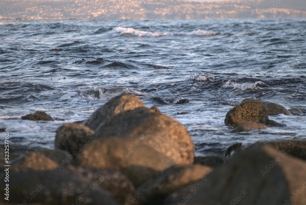 durante el ocaso se ven las olas rompiendo en las rocas de la playa