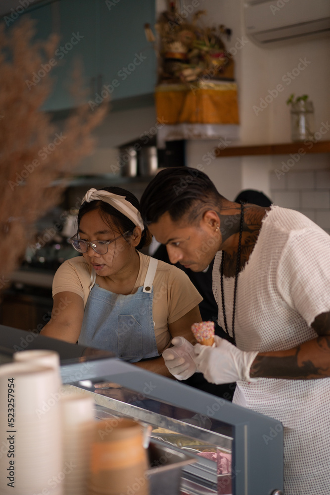 Obraz premium Young handsome mexican tattooed man making ice cream in a cone.